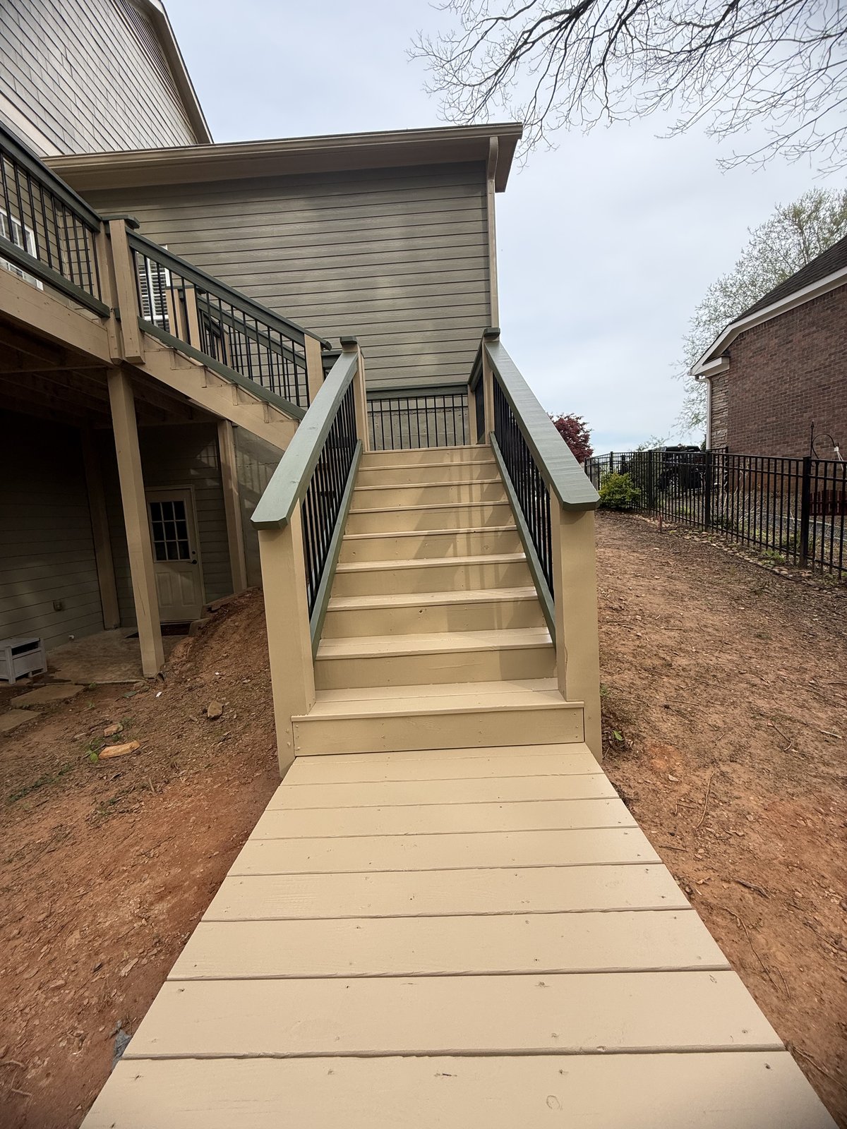 Tan-stained elevated deck with stairs descending to the yard — Lou's Atlanta Painting