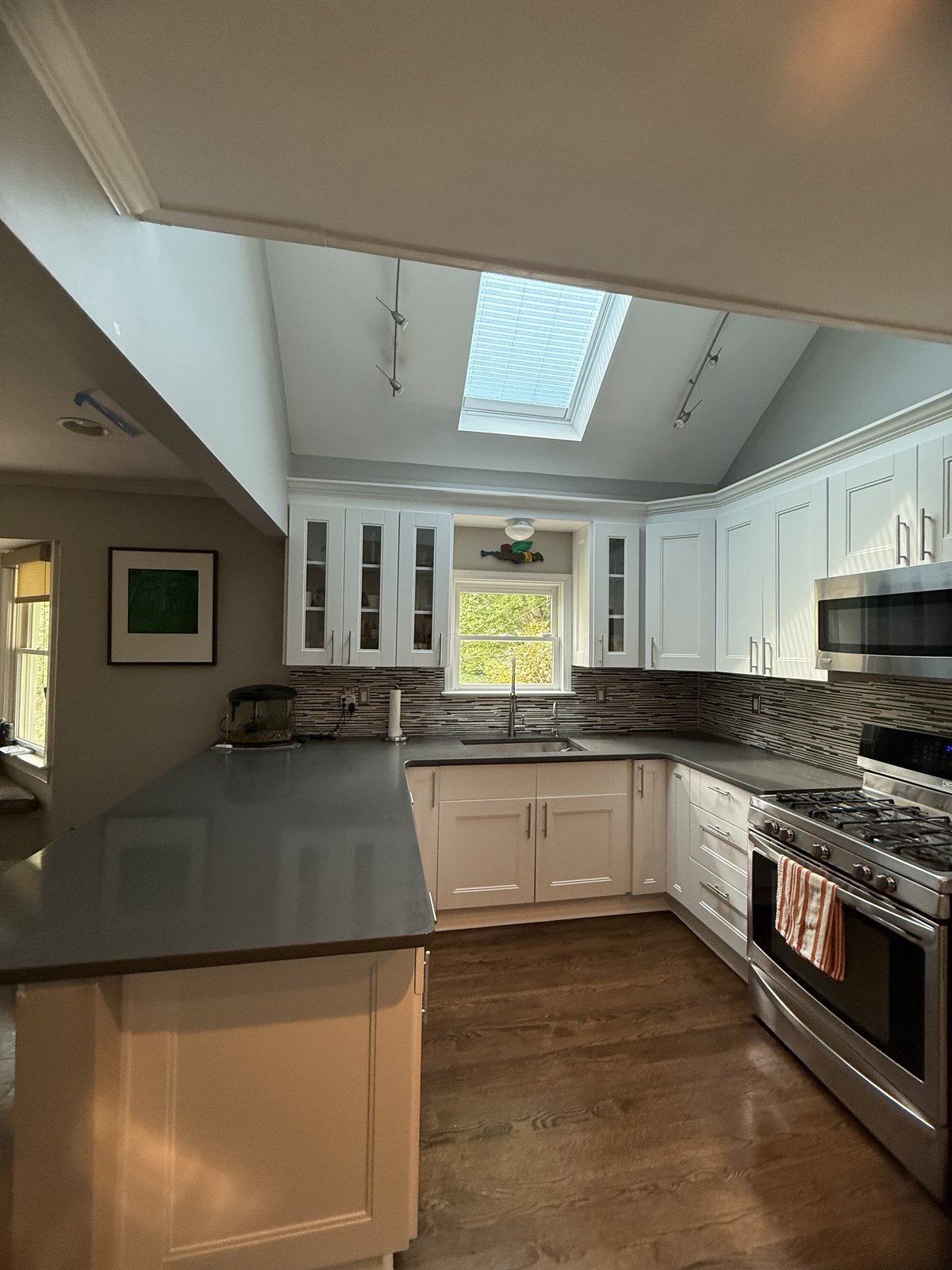 White kitchen with vaulted ceiling, skylights, and glass-front cabinets — interior repaint by Lou's Atlanta Painting
