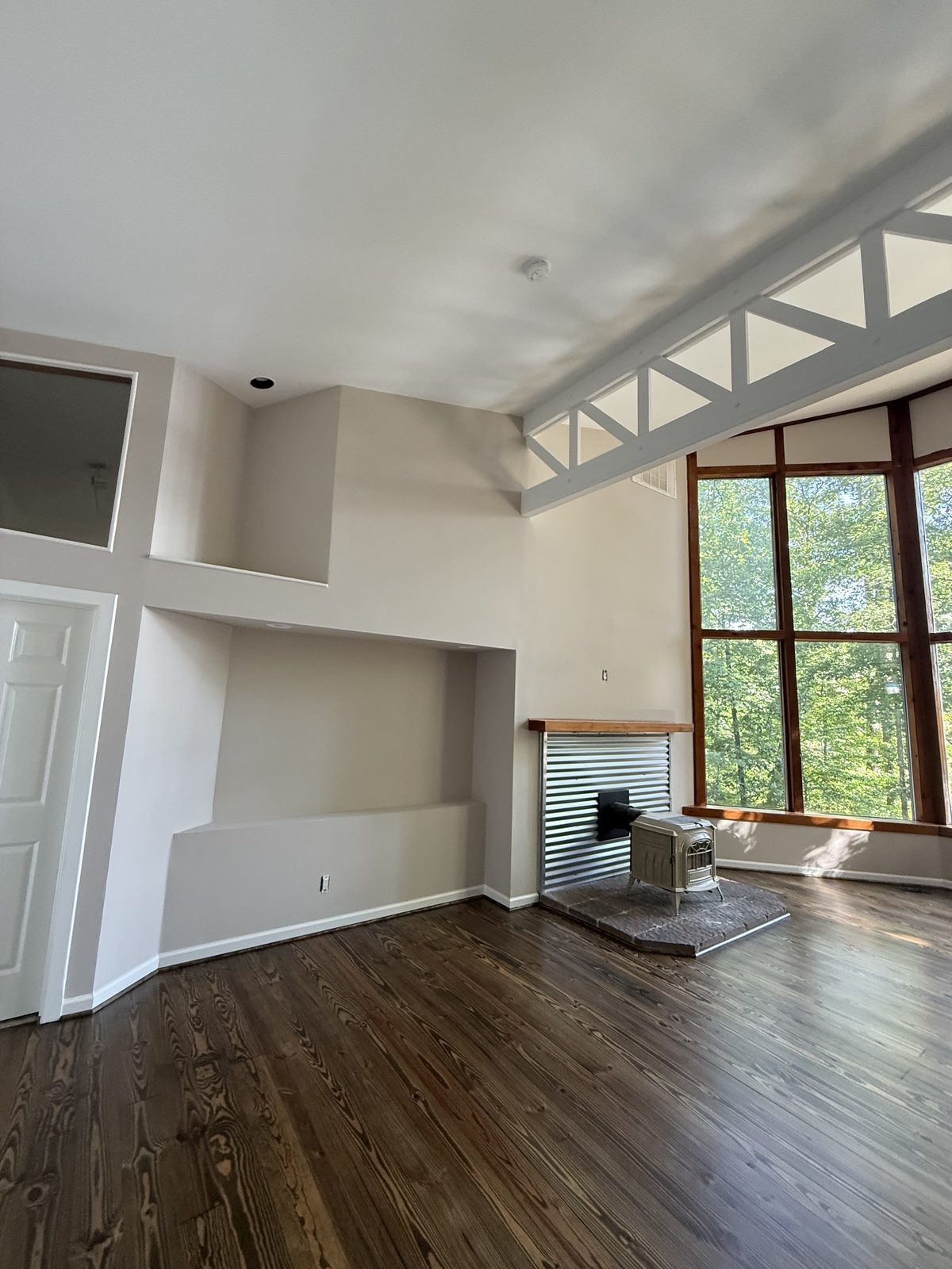 Vaulted great room with a white truss beam, wood stove, and dark hardwood floors — Lou's Atlanta Painting
