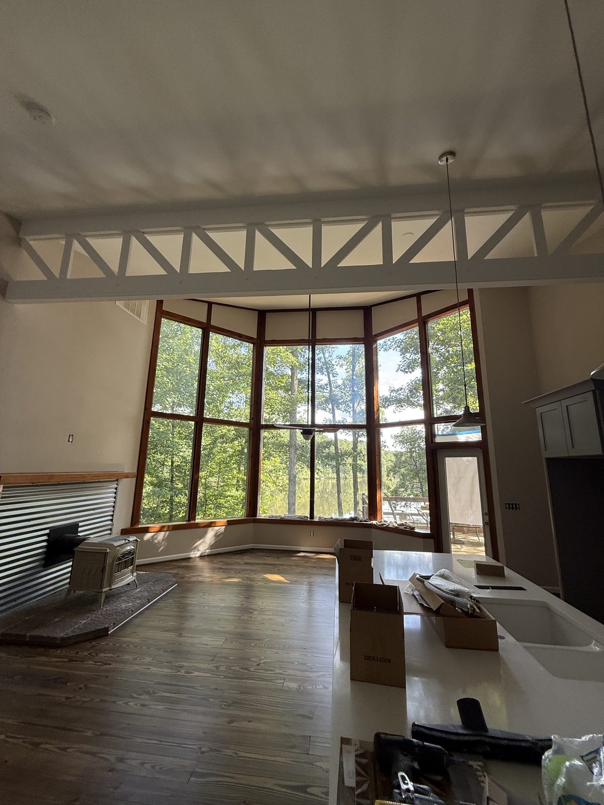Two-story great room with exposed white trusses and a bay of windows overlooking the water — Lou's Atlanta Painting
