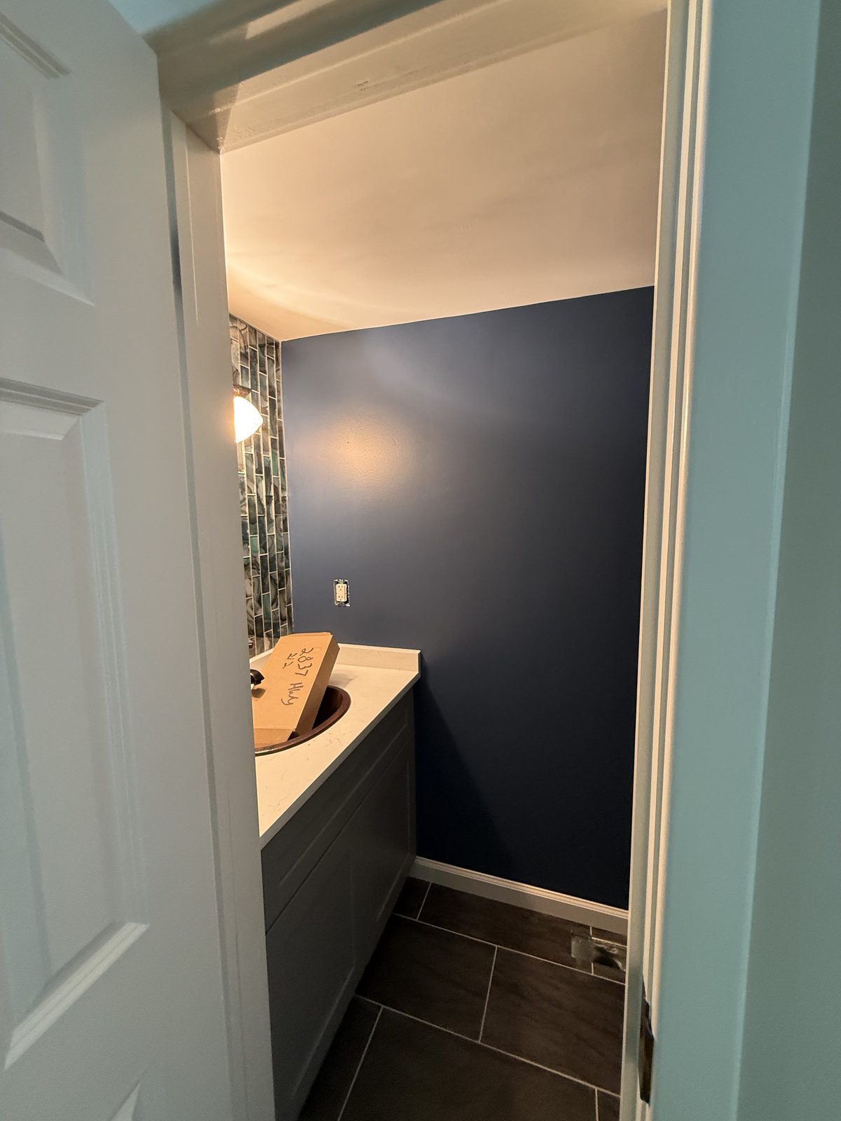 Powder room in deep navy with a glass tile accent wall and dark vanity — Lou's Atlanta Painting