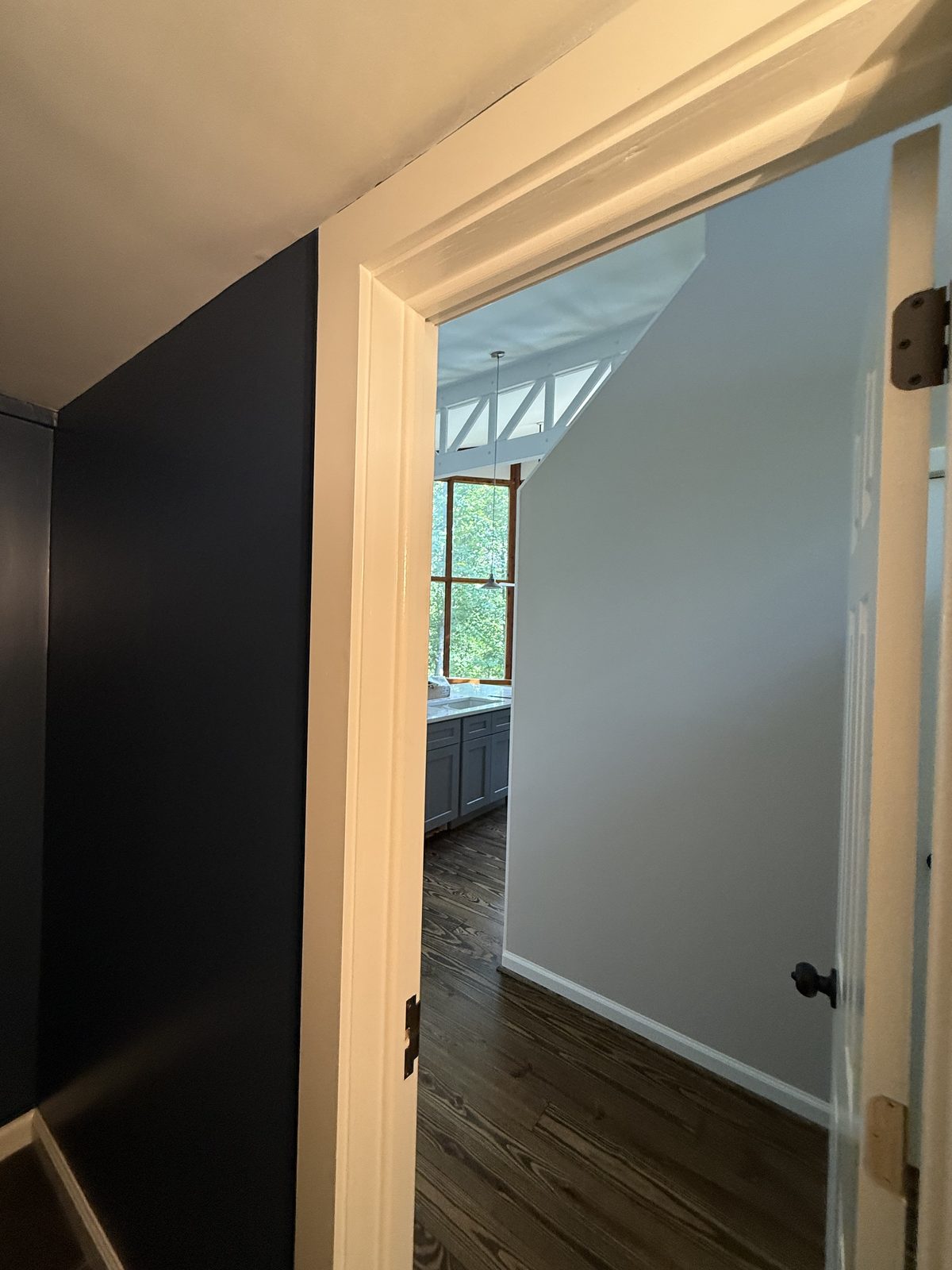 Charcoal-navy hallway opening into a soft blue room with a vaulted ceiling — Lou's Atlanta Painting