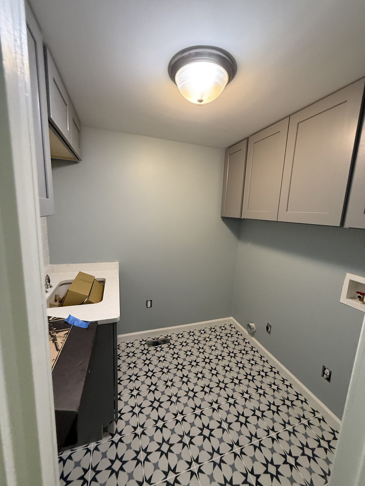 Laundry room with pale gray walls, upper cabinets, and a patterned star-motif tile floor — Lou's Atlanta Painting
