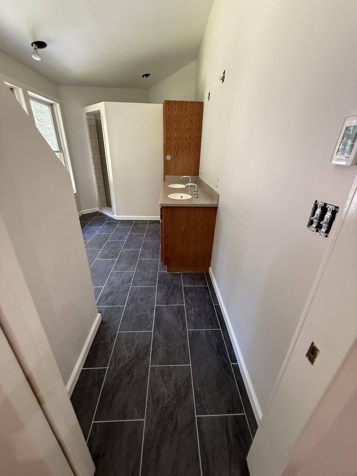 Bathroom with warm white walls, an oak vanity, and slate-look tile flooring — Lou's Atlanta Painting