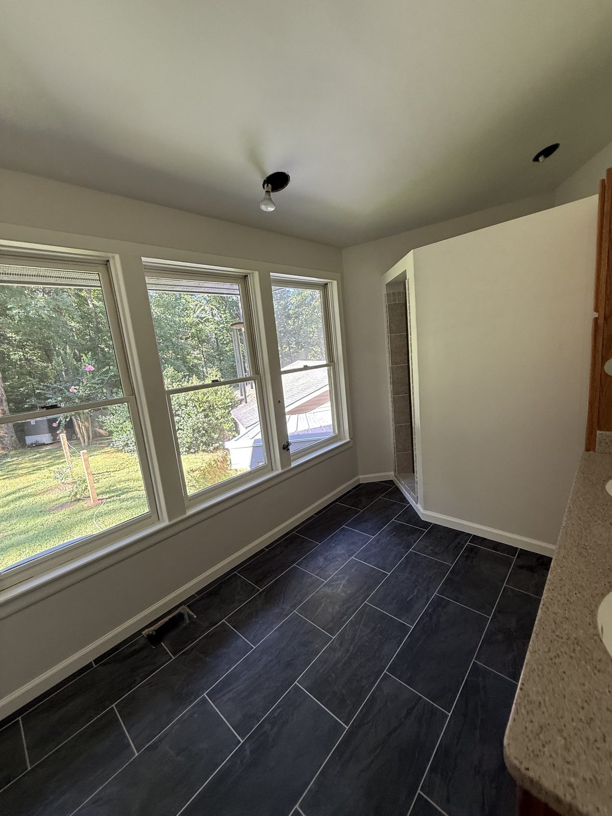 Bright bathroom corner with a bank of windows and slate-look tile flooring — Lou's Atlanta Painting