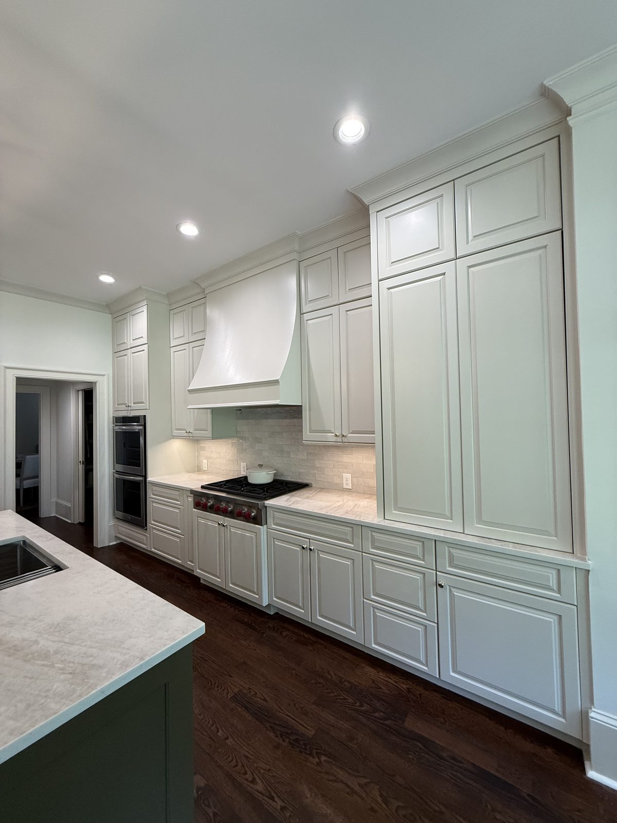 Kitchen with refinished off-white cabinetry, a white plaster range hood, and marble counters — Lou's Atlanta Painting