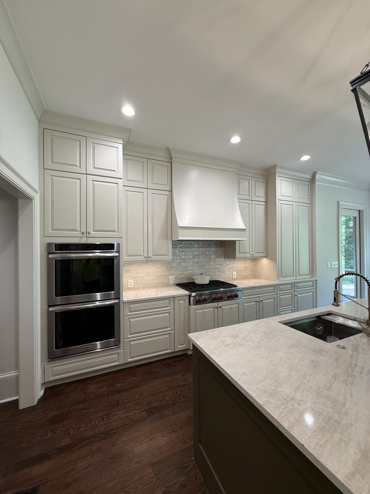 Floor-to-ceiling off-white kitchen cabinetry with double ovens and a plaster range hood — Lou's Atlanta Painting